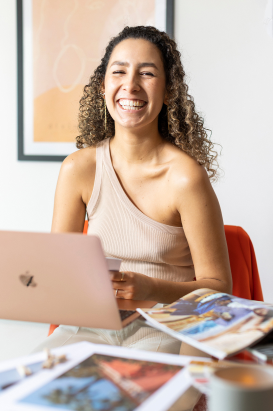 Carolina Quesada smiles to the camera while working on a laptop
